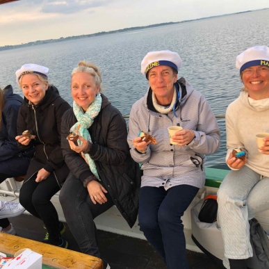 Fem kvinder nyder en kop kaffe og et stykke kage på en sejltur med træskibet Haabet.